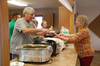 Tom Kujava scoops some stuffing into a to-go delivery container held by Trish Waage at the United Free Lutheran's free Thanksgiving Day Dinner in Greenbush on November 24, 2022. (photo by Ryan Bergeron)