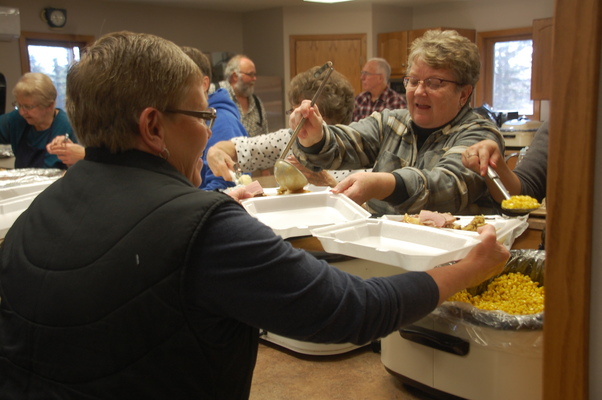 Deb Wiskow pours gravy over mashed potatoes on a to-go container that Corena Green brought through the serving line at United Free Lutheran’s annual free community Thanksgiving Day dinner event on November 23. Between deliveries, take-out, and dine-in orders, United Free served 333 meals that included turkey, ham, stuffing, mashed potatoes, corn, cranberry sauce, bun, and a dessert. Delivery areas included: Greenbush, Badger, Karlstad, Lake Bronson, Middle River, Strathcona, and Wannaska. (photo by Ryan Bergeron)